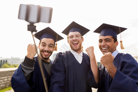 教育毕业技术成就群快乐的国际学生穿着灰浆板学士服户外自拍棒拍照庆祝快乐的男学生毕业生自拍手势高清图片素材
