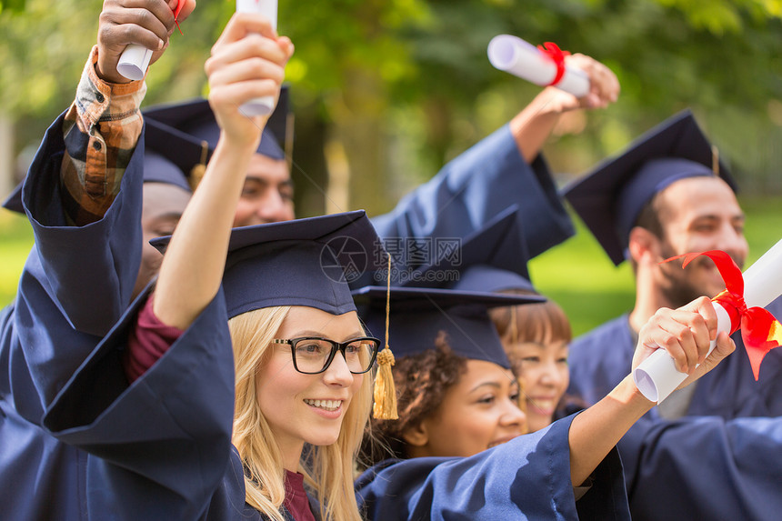 教育毕业人的群快乐的国际学生穿着灰浆板学士服,毕业证书庆祝成功文凭的迫击炮板上快乐的学生