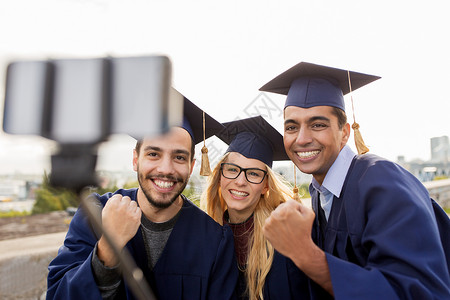 教育毕业技术成就群快乐的国际学生穿着迫击炮板学士服,户外用智能手机自拍,庆祝成功快乐的学生毕业生户外自胜利高清图片素材