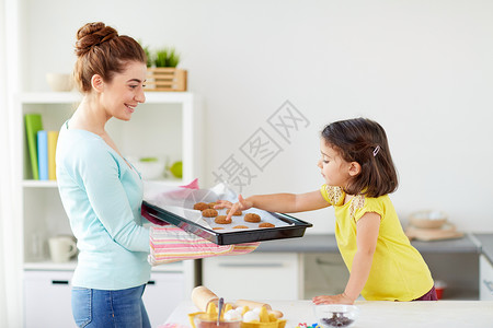 大女儿小女儿家庭,烹饪人的快乐的母亲着托盘的饼干小女儿家里的厨房快乐的母亲女儿家烤饼干背景