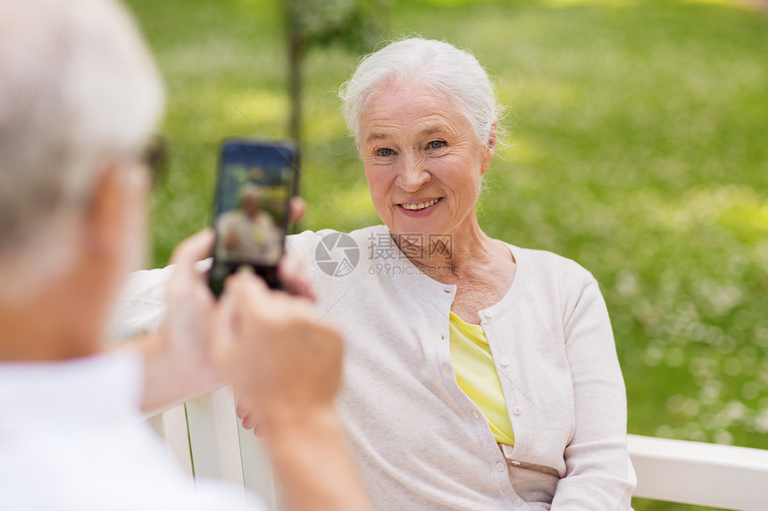 技术,退休老人的快乐的微笑老夫妇与智能手机拍照夏季公园老妇人公园用智能手机给男人拍照图片