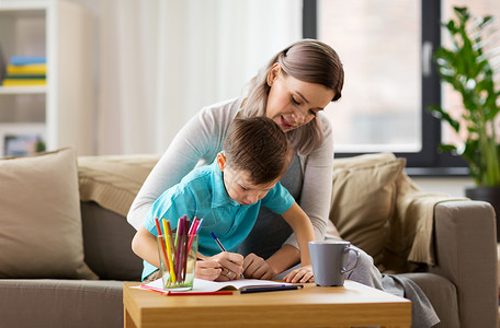 家庭教育快乐的母亲小儿子家里写作业本画画母亲儿子家带着工作簿图片