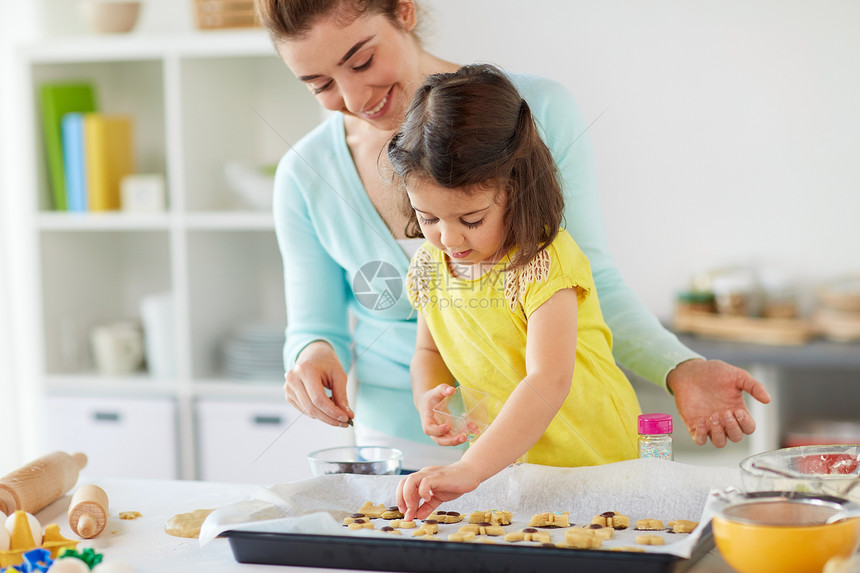 家庭,烹饪烘焙快乐的母亲小女儿用巧克力洒家庭厨房的托盘上装饰饼干快乐的母亲女儿家饼干图片