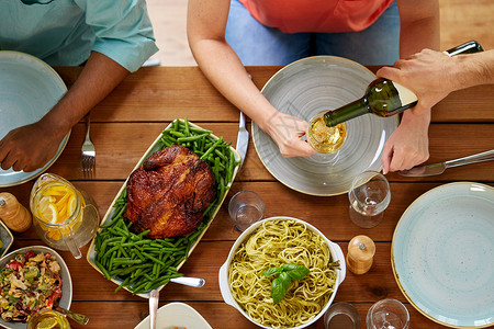 感恩节,饮食休闲群人餐桌上吃晚饭,喝葡萄酒群人吃喝葡萄酒背景图片