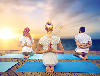 健身健康的生活方式群人瑜伽反向祈祷姿势木墩上的海洋背景群人户外瑜伽图片