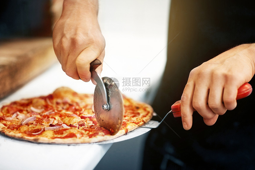 食物,意大利厨房烹饪比萨饼店用切割机切割比萨饼比萨饼店把比萨饼切成碎片图片