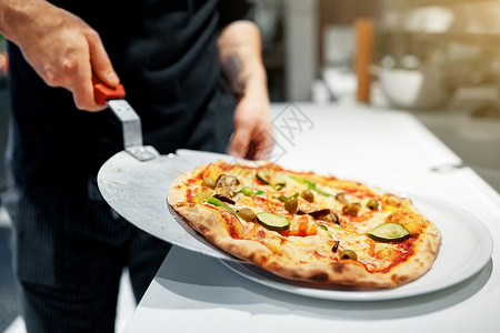 食物烹饪,烹饪人的厨师包师把比萨饼果皮盘子比萨饼店披萨店用烤披萨皮饼背景图片