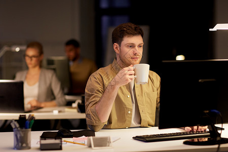 咖啡男人商业,截止日期技术男人电脑工作喝咖啡夜间办公室带笔记本电脑咖啡的男人夜间办公室工作背景