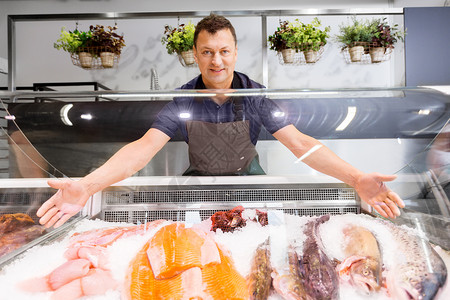 食品销售,小企业人的男卖家展示海鲜鱼店冰箱卖海鲜的男鱼店冰箱里展示海鲜图片