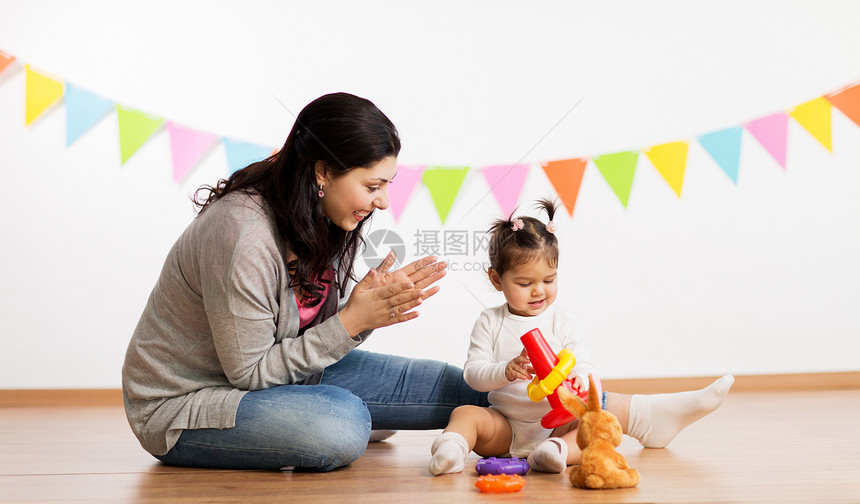 家庭,假期人的快乐的母亲为小女儿生日聚会上玩环形金字塔婴儿玩具鼓掌母女玩金字塔玩具母女玩金字塔玩具图片