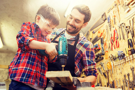 家庭,木工,木工人的父亲小儿子车间用钻孔木板父亲儿子车间工作父亲儿子车间工作背景图片