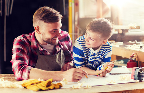 铅笔与男孩家庭,木工,木工人的快乐的父亲小儿子与蓝图车间快乐的父子蓝图车间快乐的父子蓝图车间背景