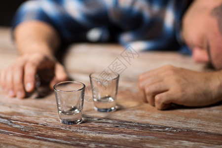 酒精成瘾人的男酒精,空眼镜,躺桌子上晚上睡觉晚上桌子上戴着空眼镜的醉汉晚上桌子上戴着空眼镜的背景图片