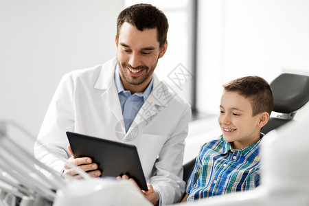 医学,牙科医疗微笑的男牙医向牙科诊所的儿童病人展示平板电脑牙医诊所向儿童病人展示平板电脑牙医诊所向儿童病人背景图片