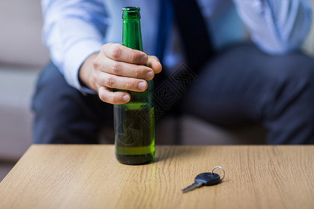 酒后酗酒,醉酒驾驶人的男司机的手与啤酒瓶汽车钥匙桌子上桌子上啤酒瓶汽车钥匙的男手桌子上啤酒瓶汽车背景