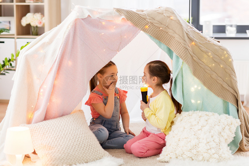 童,潮湿友谊的小女孩与火炬光孩子帐篷帐篷家里玩孩子们家里的帐篷里放着手电筒的小女孩孩子们家里的帐篷里图片