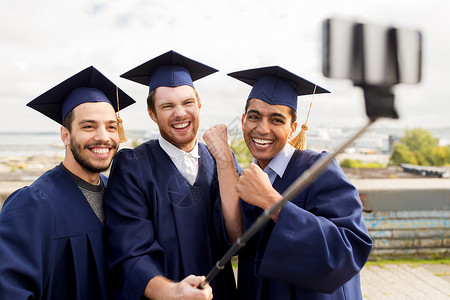 教育毕业技术成就群快乐的国际学生穿着灰浆板学士服户外自拍棒拍照庆祝快乐的男学生毕业生自拍快乐的男学礼服高清图片素材