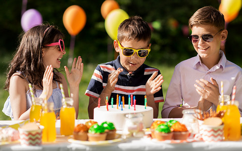 拿着蜡烛男孩假期,童庆祝快乐的孩子蛋糕上着蜡烛,坐夏天的花园聚会上,为生日男孩鼓掌快乐的孩子夏天的生日聚会上吃蛋糕背景