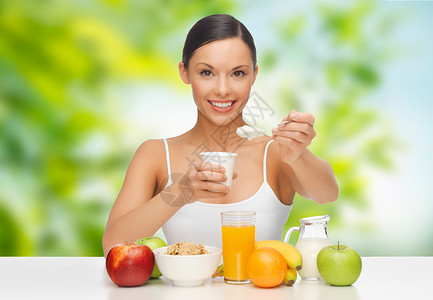 饮食,健康食品人的女人与水果吃酸奶早餐绿色的自然背景带水果的女人早餐吃酸奶带水果的女人早餐吃酸奶背景图片