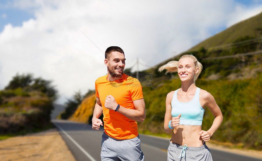 健身,运动健康的生活方式微笑的夫妇与心率手表运行大苏尔山道路背景加利福尼亚微笑的夫妇跑过大丘微笑的图片