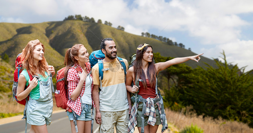 冒险,旅行,旅游,徒步旅行人们的群微笑的朋友,背包指着加州海岸的大山丘背景群朋友带着背包大丘上群朋友带着图片