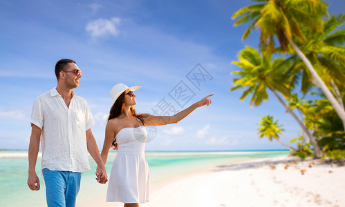 旅行,旅游暑假的快乐的夫妇度假时戴着太阳镜,手牵手热带海滩背景下行走法属波利尼西亚快乐的夫妇热带海滩度假背景图片