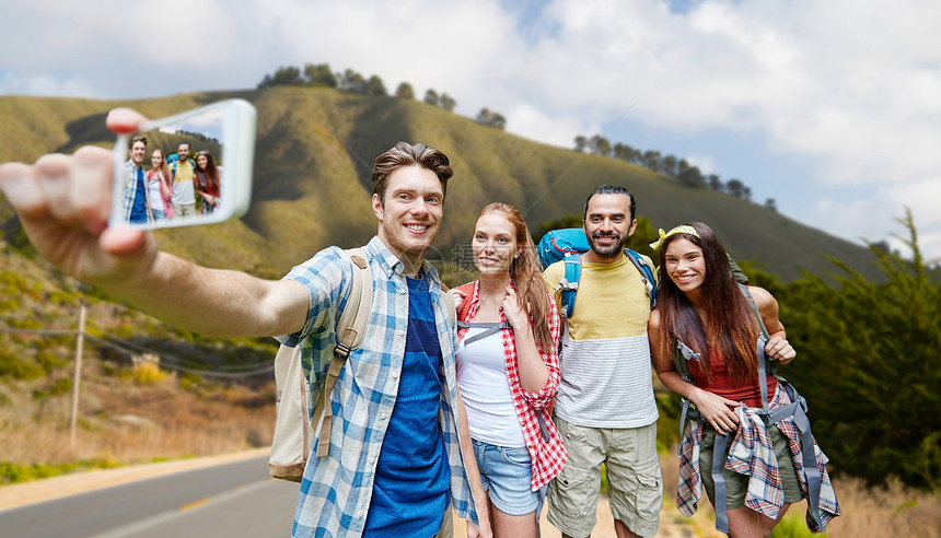 技术,旅游,徒步旅行人的群微笑的朋友背包,用智能手机自拍,加州大山的背景下背包的朋友用智能手机自拍
