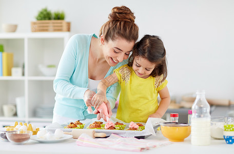 食物和女孩妈妈和女儿在家制作纸杯蛋糕背景