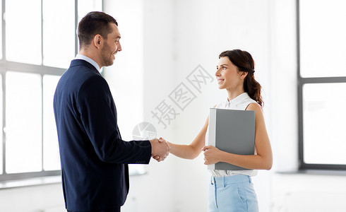 商人,合作伙伴合作理念快乐微笑的女商人与文件夹商人办公室握手女商人商人握手背景图片