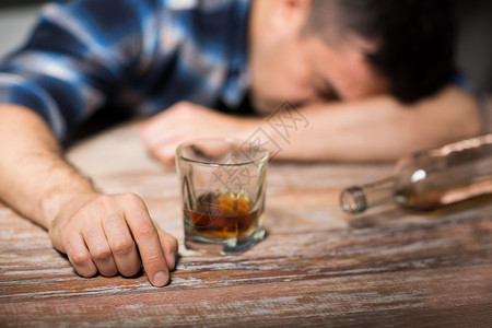 男酒精与杯威士忌瓶子躺桌子上晚上睡觉晚上桌子上喝了杯酒的醉汉背景图片