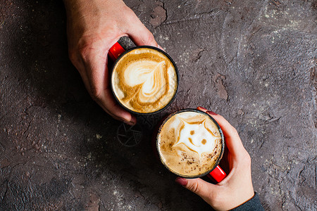 两只手着杯热咖啡黑暗的背景,顶部的视野为相爱的夫妇喝早咖啡图片