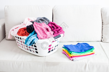放衣服篮子篮子里洗衣服,沙发上放叠干净的亚麻布五颜六色的干净衣服背景