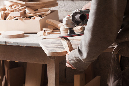 工人抛光木桌,木匠用电砂机打磨木材用于木材的砂光机背景图片