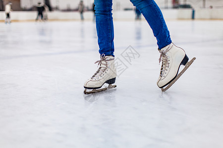 轻的女人溜冰场上滑冰,闭上双腿溜冰鞋溜冰场上背景图片