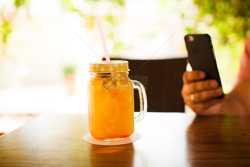 杯装满新鲜橙汁鸡尾酒吸管的木桌男人移动摄影新鲜的橙色乐趣图片