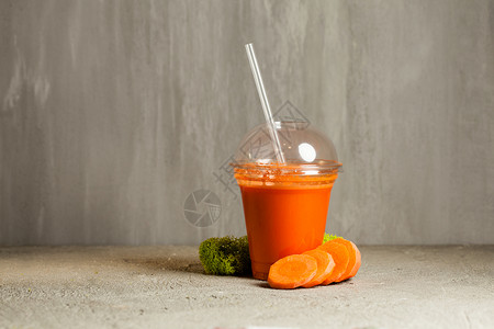 塑料杯胡萝卜汁附近新鲜蔬菜新鲜胡萝卜汁背景图片