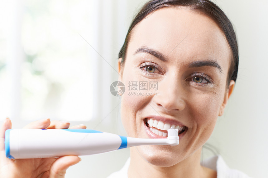 女人浴室用电动牙刷刷牙图片