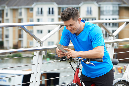 轻人城市环境中用手机骑自行车背景图片
