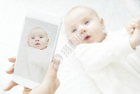 妈妈手机上给女婴拍照图片