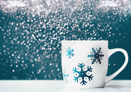 白色杯子与雪花桌子上的蓝色背景与bokeh,正视图的寒假布置光高清图片素材
