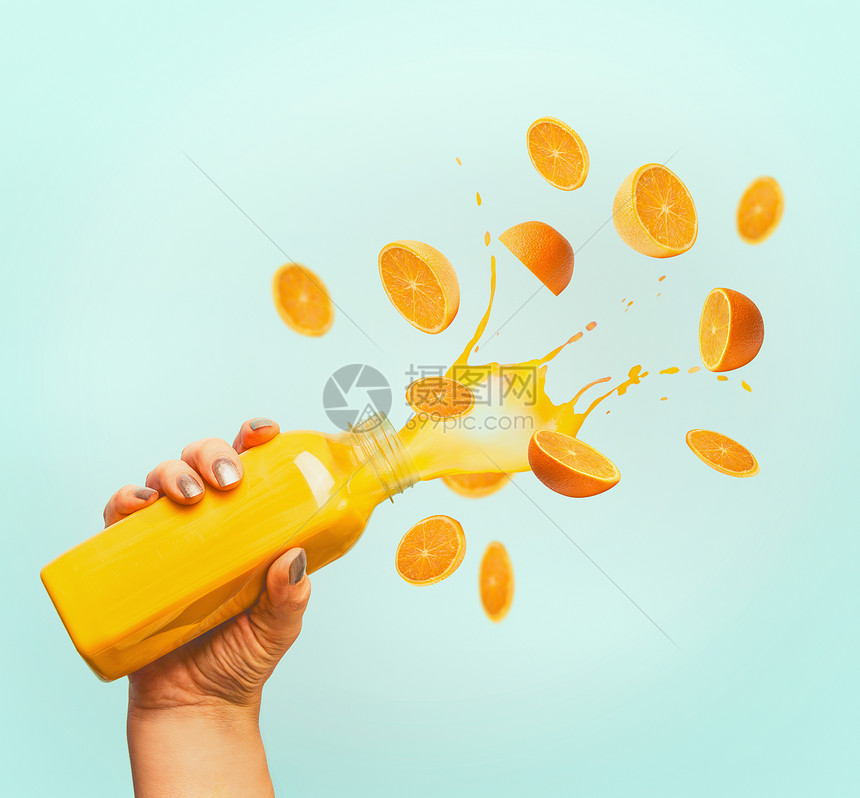 女手瓶黄色飞溅夏季饮料冰沙果汁飞行橘子蓝色背景图片