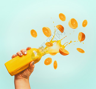 女手瓶黄色飞溅夏季饮料冰沙果汁飞行橘子蓝色背景图片