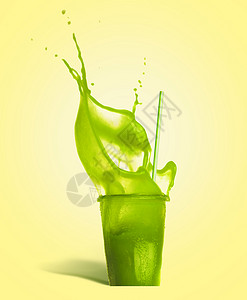 璃与饮用吸管绿色飞溅夏季饮料冰沙果汁黄色背景,正视图图片