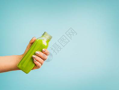 女手瓶与绿色夏季饮料冰沙果汁蓝色背景图片