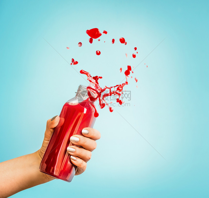 女手瓶与红色飞溅夏季饮料冰沙果汁蓝色背景图片
