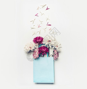 新鲜可爱的花蓝色纸购物袋白色桌背景,顶部视图,背景图片