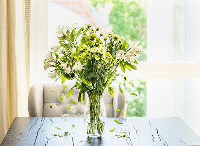 美丽的绿色花与落璃花瓶桌子上的璃花瓶阳光明媚的客厅窗口家庭内部装饰的想法背景图片