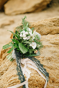 来自粪便玫瑰的新娘躺海边的砂岩石上背景图片