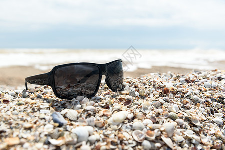 太阳镜躺海边的沙子里背景图片