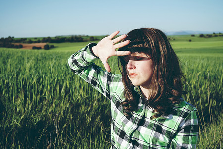 阳光明媚的日子里,轻的女人独自绿色的田野里蓝色高清图片素材